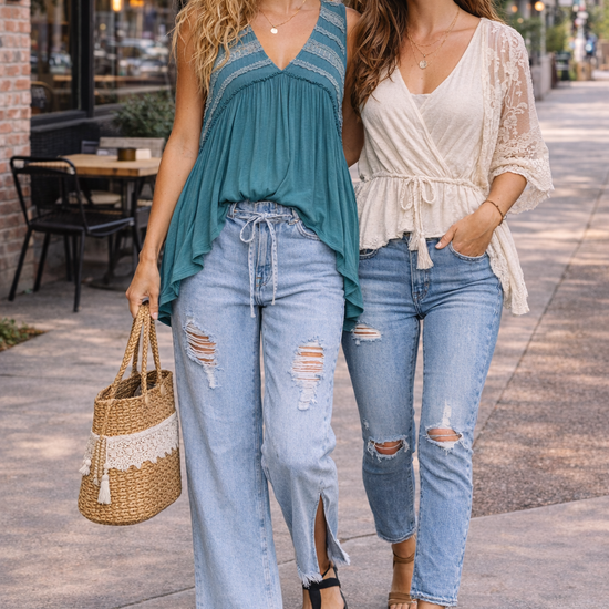 Two women walking in casual boho outfits featuring a teal flowy top and light wash distressed wide leg jeans styled for everyday wear