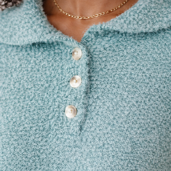 close-up of teal textured boucle sweater showing soft fabric detail and button front design on African American model