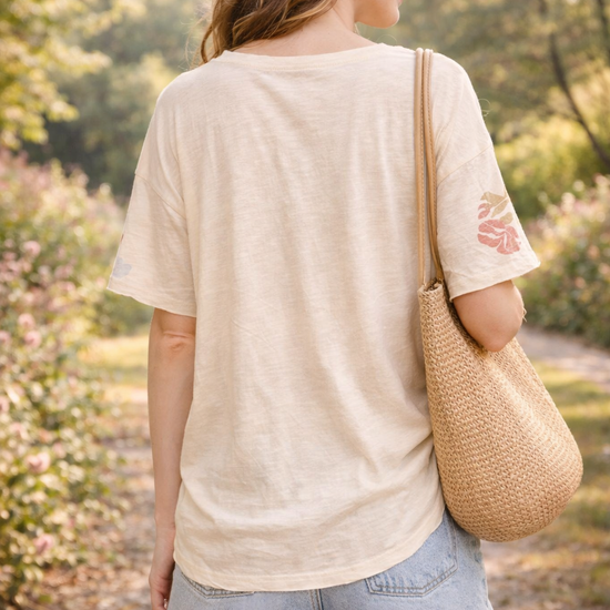 Back view of women's boho butterfly floral graphic tee styled with denim shorts in a relaxed boutique summer outfit