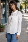 woman wearing a lightweight white button-up blouse styled in a casual outdoor street setting