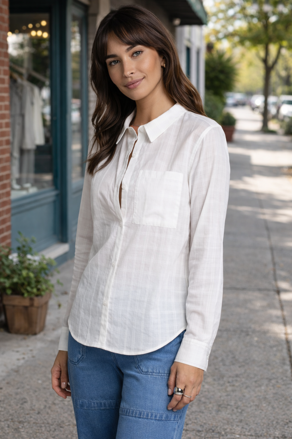 woman wearing a lightweight white button-up blouse styled in a casual outdoor street setting