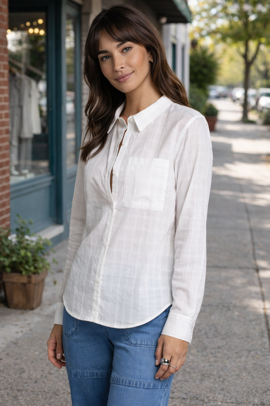 woman wearing a lightweight white button-up blouse styled in a casual outdoor street setting
