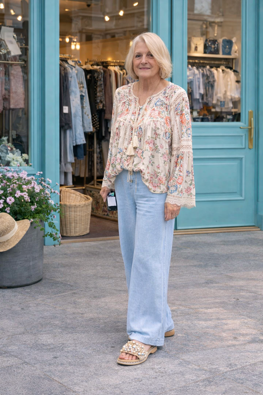 woman wearing light wash wide leg denim pants with flowy boho blouse styled outside boutique with turquoise doors