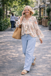 woman wearing light wash wide leg denim pants and flowy boho blouse walking outdoors