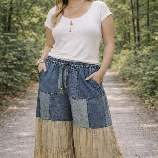 Plus size woman wearing Young Threads boho patchwork flares styled with a white fitted top, standing on a tree-lined outdoor path