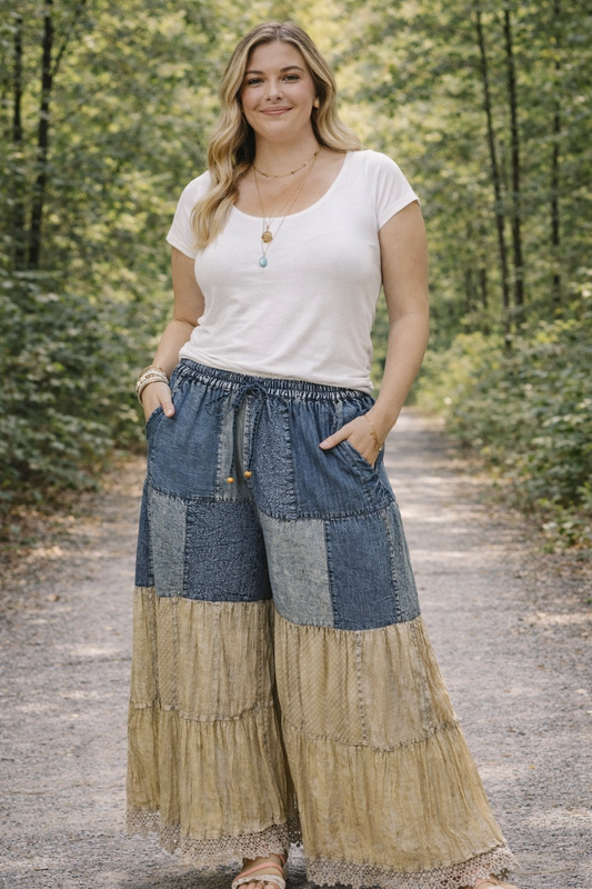 Plus size woman wearing Young Threads boho patchwork flares styled with a white fitted top, standing on a tree-lined outdoor path